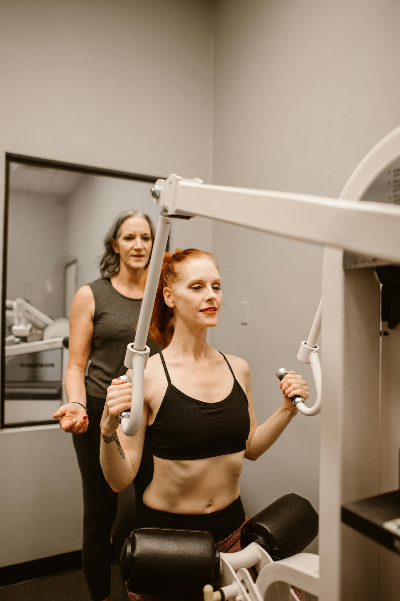 Women working out on exercise machine in gym, focused on fitness and health.
